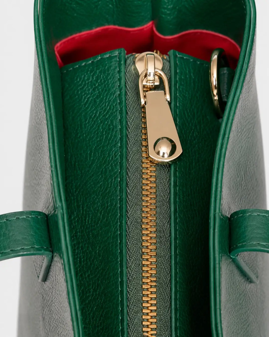 Emerald green leather tote bag with double shoulder straps and red decorative tassels close zipper shot
